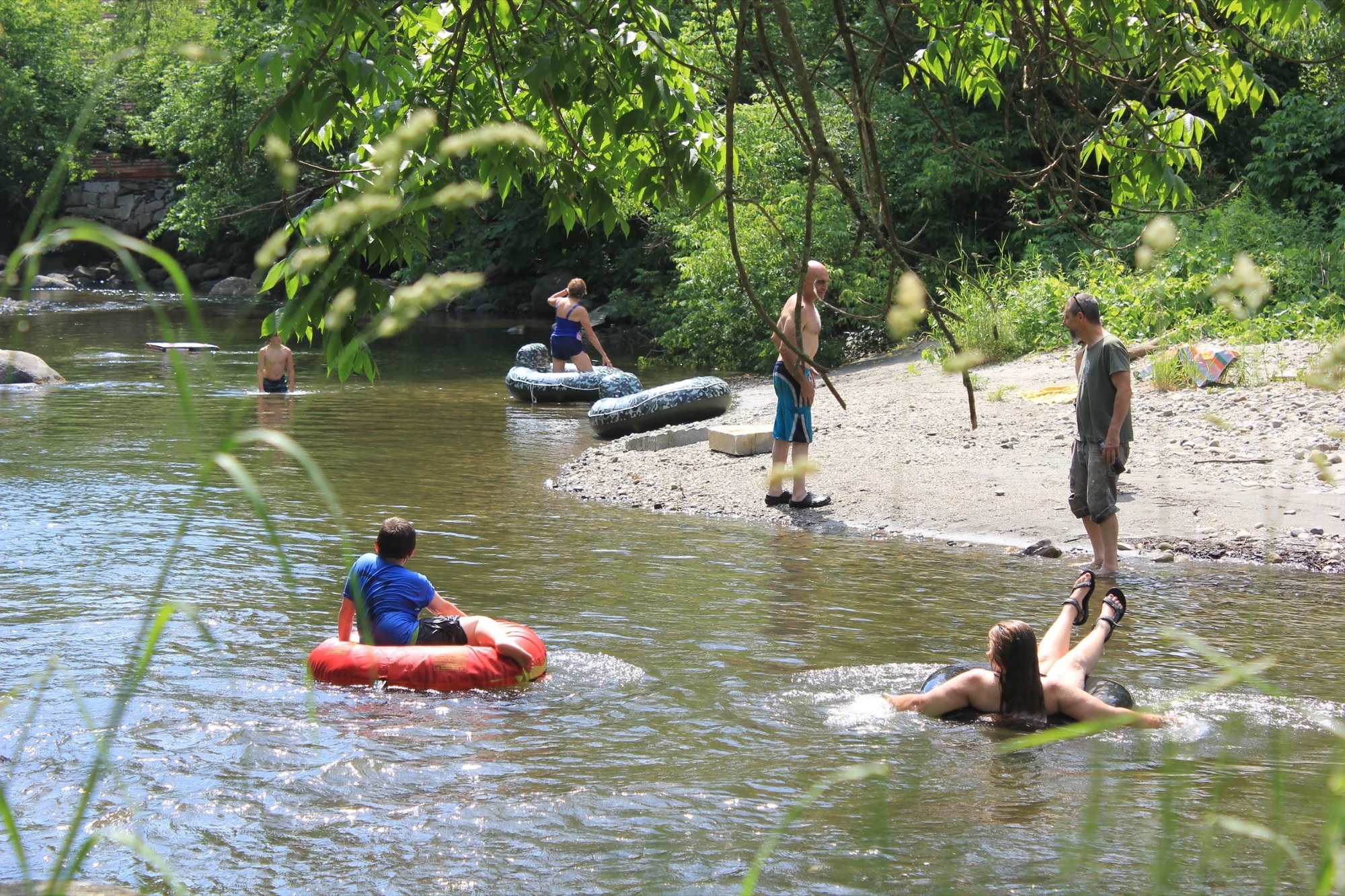 Campers floating and wading in the Winooski River beside the campground