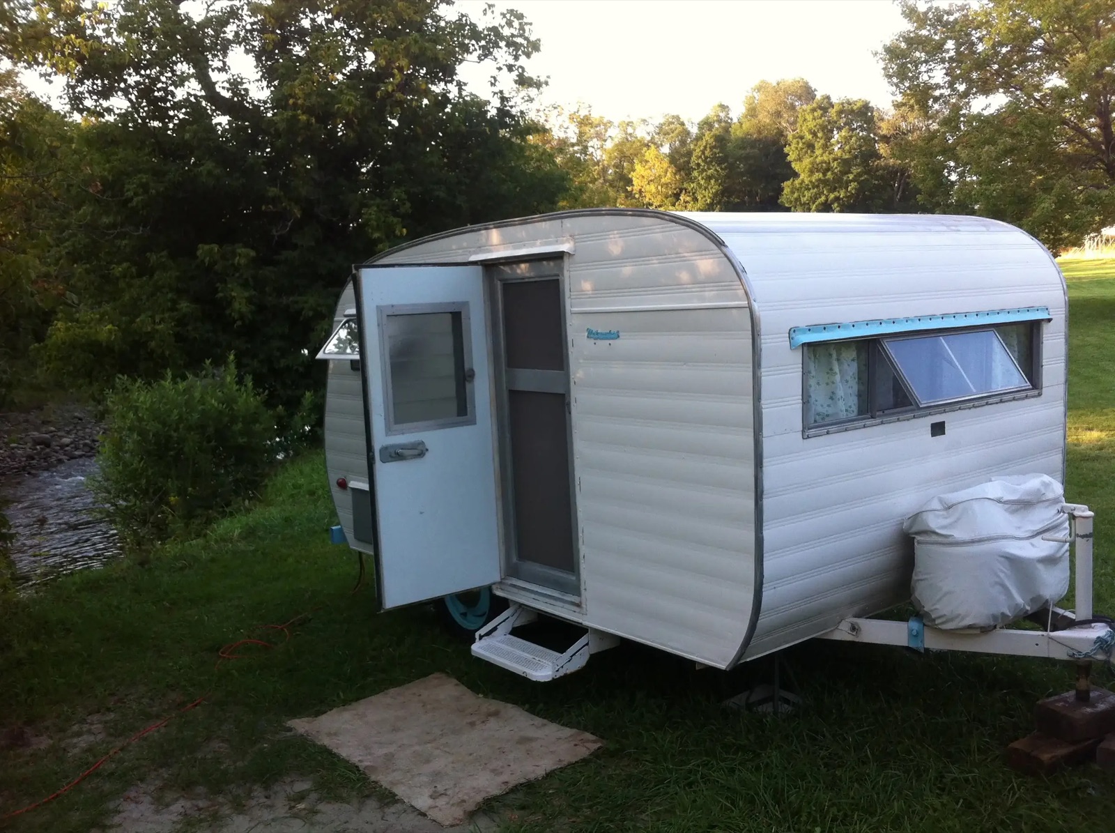 A vintage white camper trailer on a grassy site